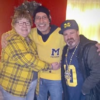 Three customers wearing Michigan apparel pose together inside Casey’s Toledo.