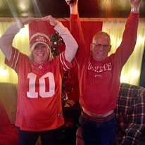 Two customers in scarlet Ohio State shirts raise their arms in celebration at Casey’s Toledo.